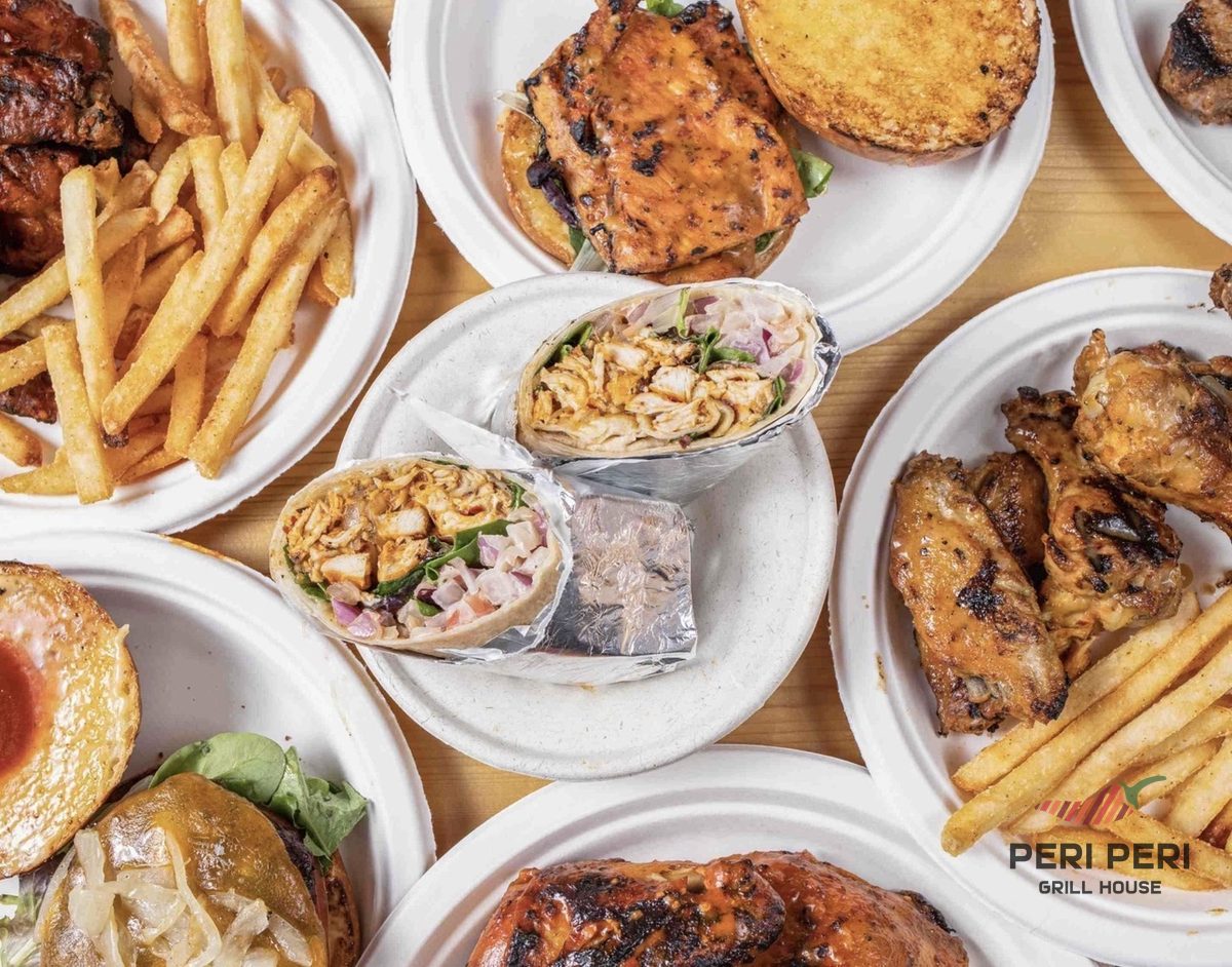 Overhead view of Peri Peri Grill House dishes — wings, grilled chicken, wrap, fries and burgers